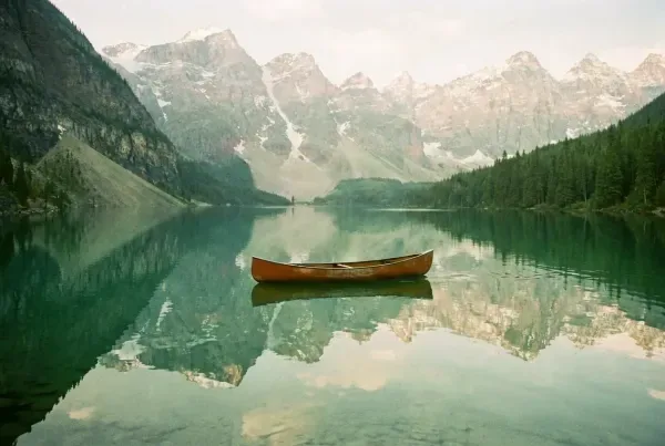 Alpiner See bei Banff im ersten Licht mit einsamem Kanu vor Cascade Mountain