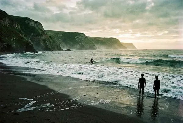 Atlantikküste bei Sagres im Sonnenaufgang mit einsamem Surfer auf dem Wasser
