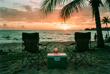 Zwei Campingstühle Richtung Ozean bei Sonnenuntergang auf den Florida Keys mit Palmschatten und Cocktail